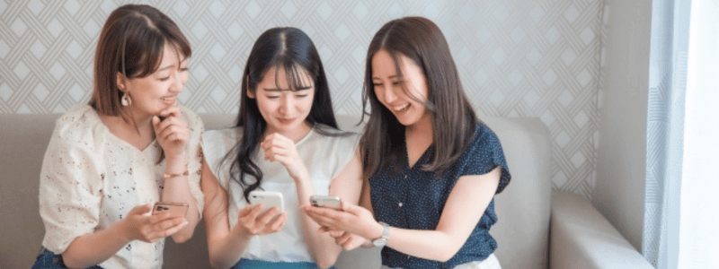 スマホの画面を見せ合っている女性